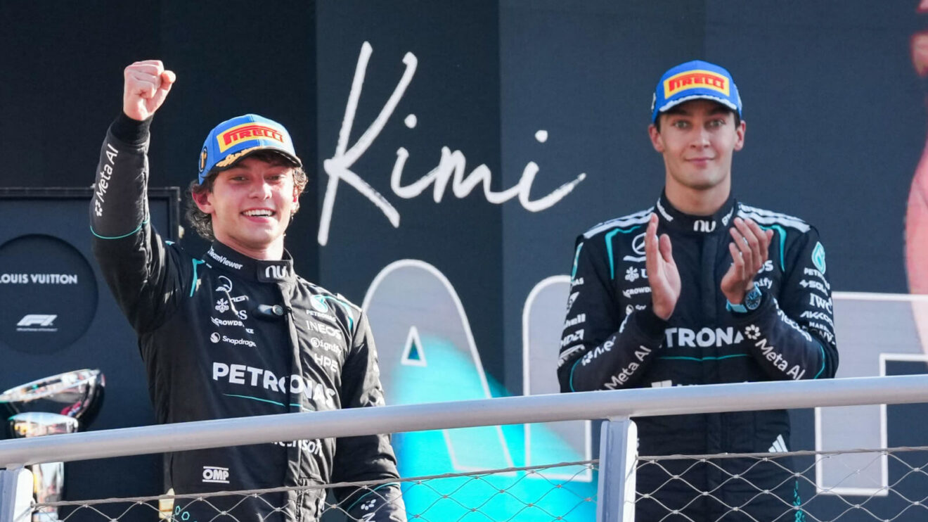 Kimi Antonelli raises his fist as he steps on the podium, George Russell clapping