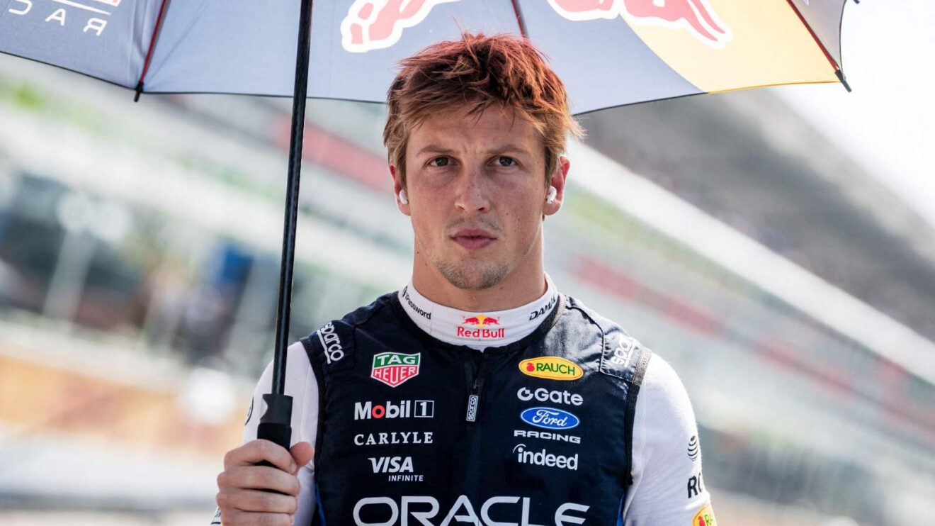 Liam Lawson holds a Red Bull-branded umbrella on the grid.