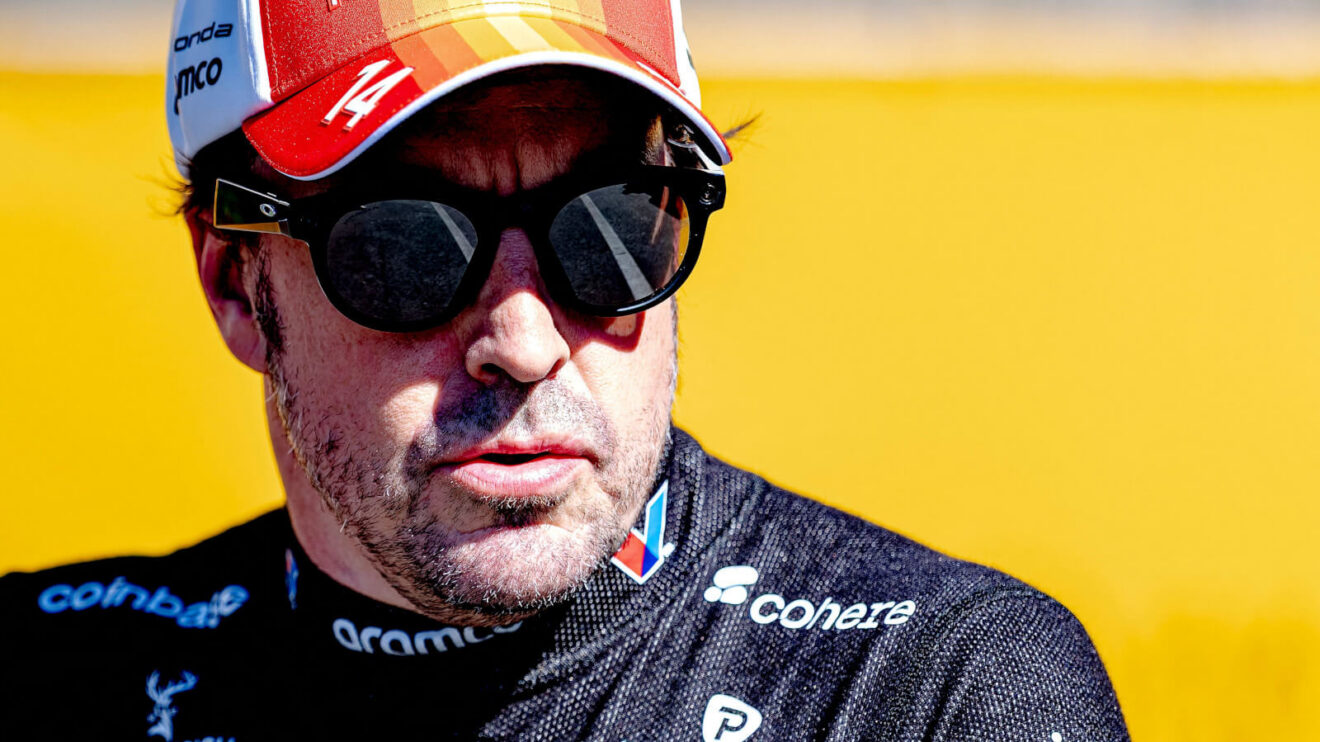 Fernando Alonso wearing sunglasses and Aston Martin's Spanish GP cap looking off to the side