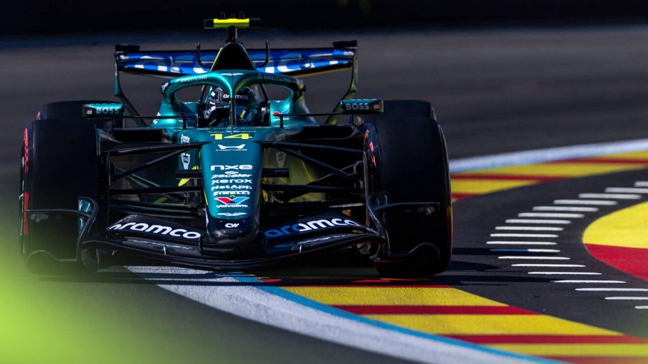 An action shot of Fernando Alonso's Aston Martin running over yellow-and-red kerbs in Madrid