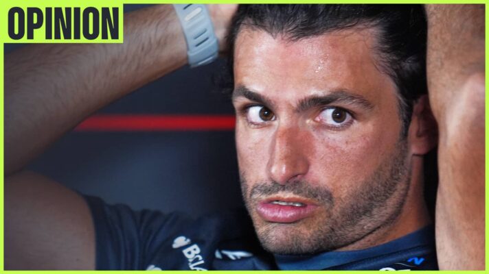 Carlos Sainz looks strained as he holds his hands on his head in a press conference. An 'opinion' tab sits in the top-left corner