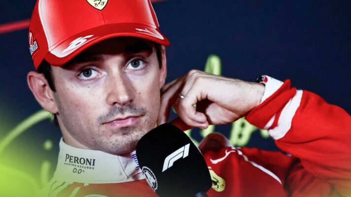 Charles Leclerc strokes his neck while holding a microphone in a press conference