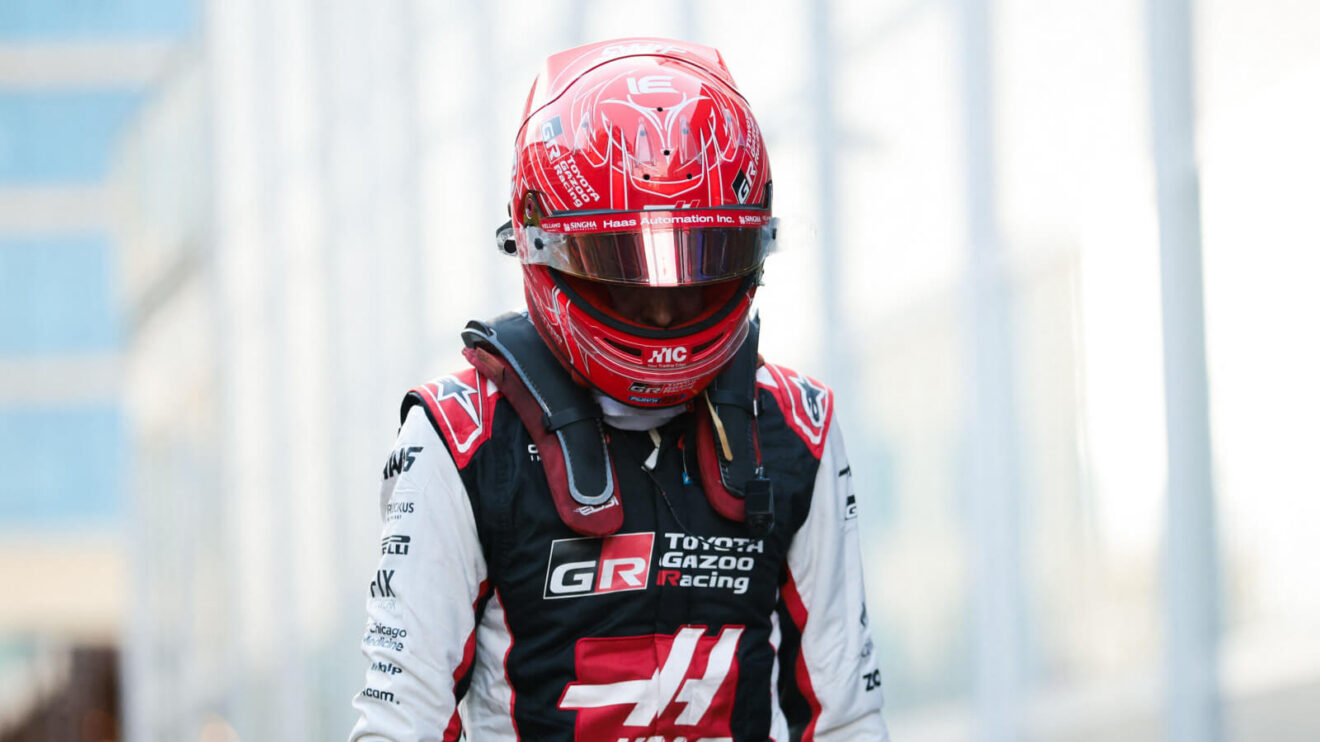 Esteban Ocon walking through the paddock with his head down and his helmet on