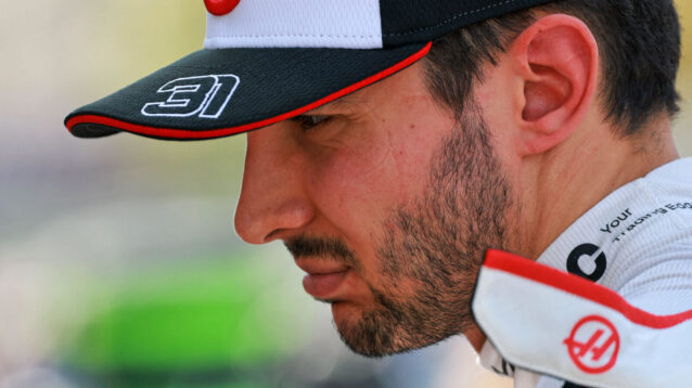 Esteban Ocon looking forward, wearing Haas cap