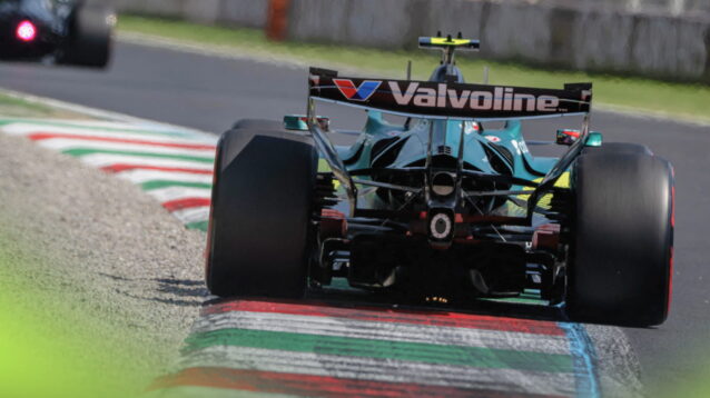 A rear-facing shot of Fernando Alonso's Aston Martin running over a kerb painted in the green, white and red colours of the Italian flag at Monza
