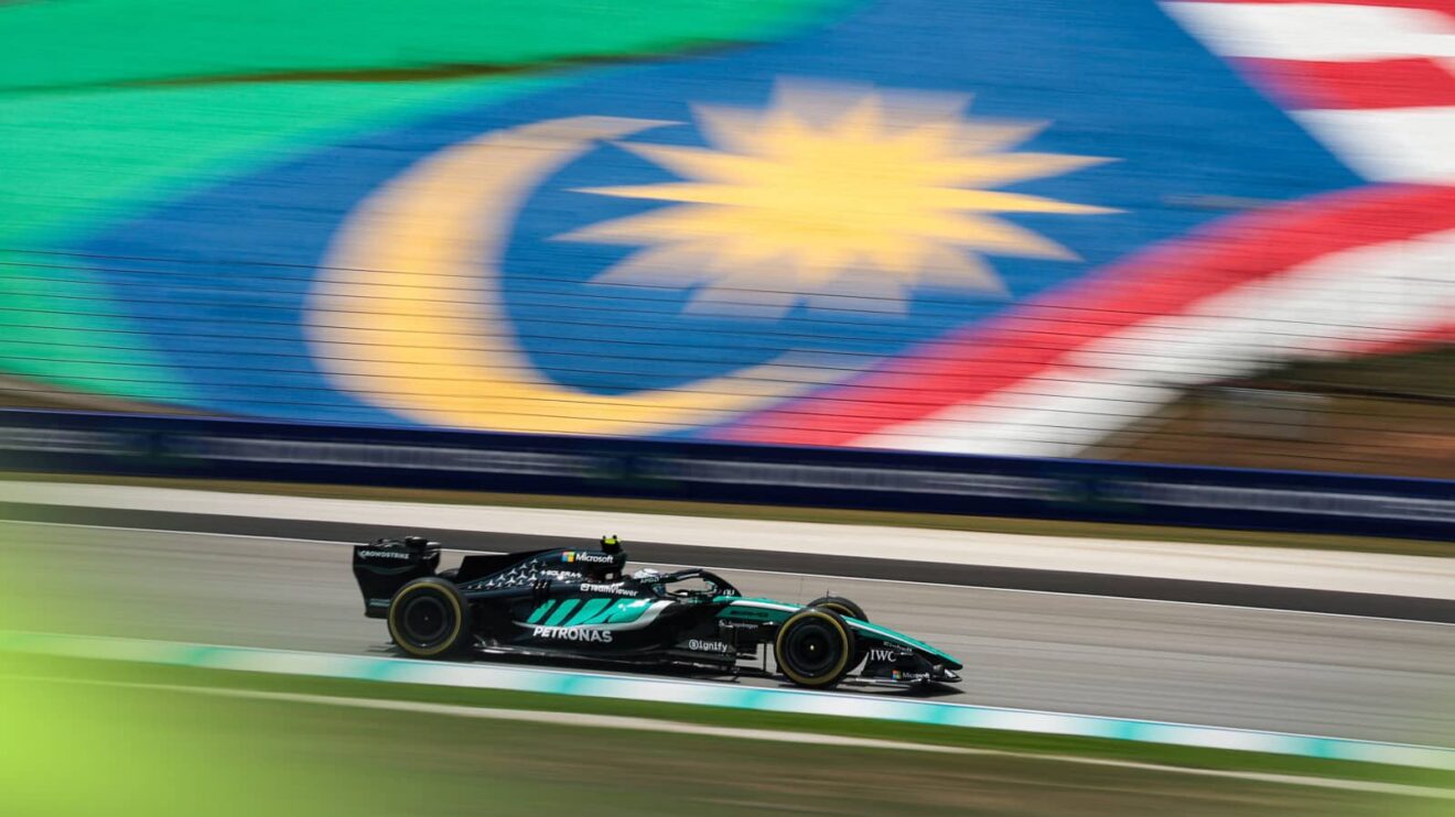 Kimi Antonelli's Mercedes on track at Sepang with a giant Malaysia flag in the background