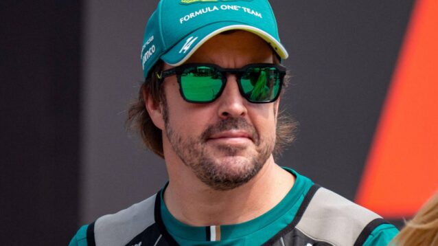 Fernando Alonso walks through the paddock wearing a cooling vest.