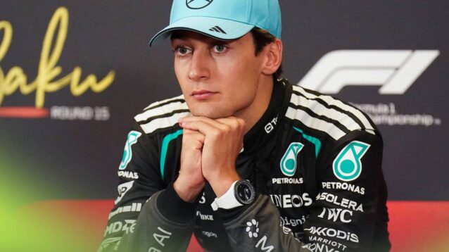 George Russell sits with his chin resting on his hands in a press conference