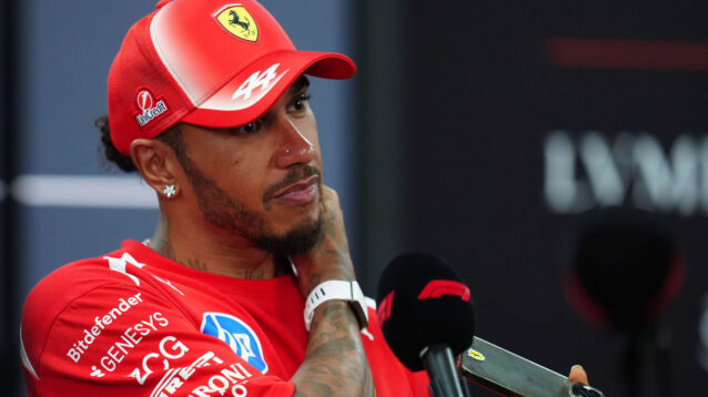 Lewis Hamilton hand on his neck as he speaks to the media