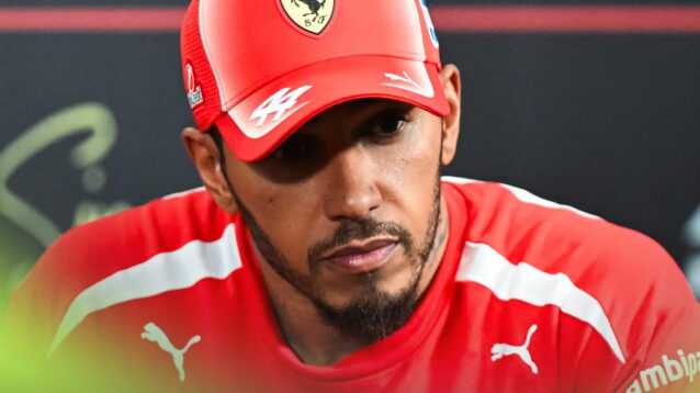 Lewis Hamilton sits in a press conference with the shadow from the peak of his cap over his eyes
