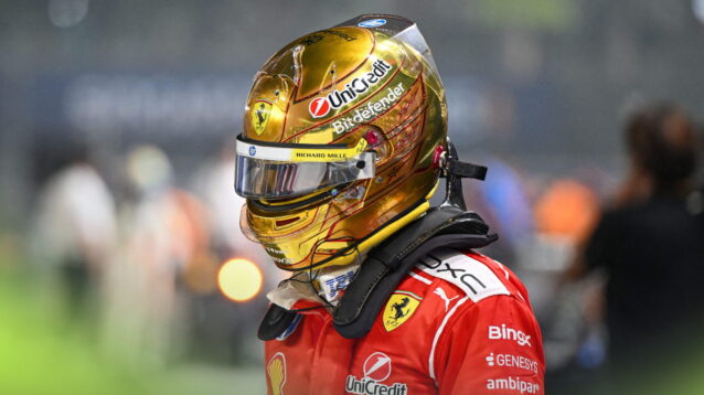 Lewis Hamilton wearing a gold helmet and red Ferrari race suit in the Singapore pit lane