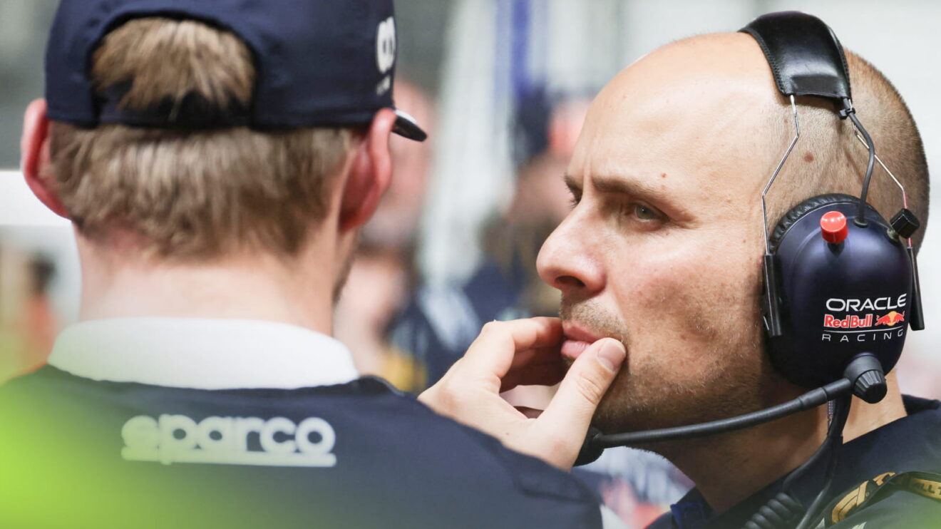 GianPiero Lambiase holds his hand to his mouth while in conversation with Max Verstappen, who has his back to the camera
