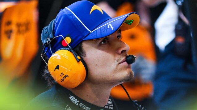 Lando Norris wearing a headset in the McLaren garage.