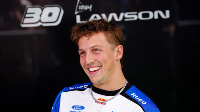 Liam Lawson, standing in front of his name and his No30, smiling
