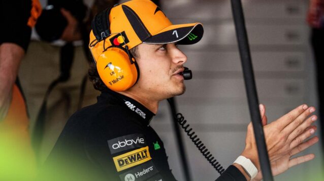 Lando Norris wears a headset in the McLaren garage.